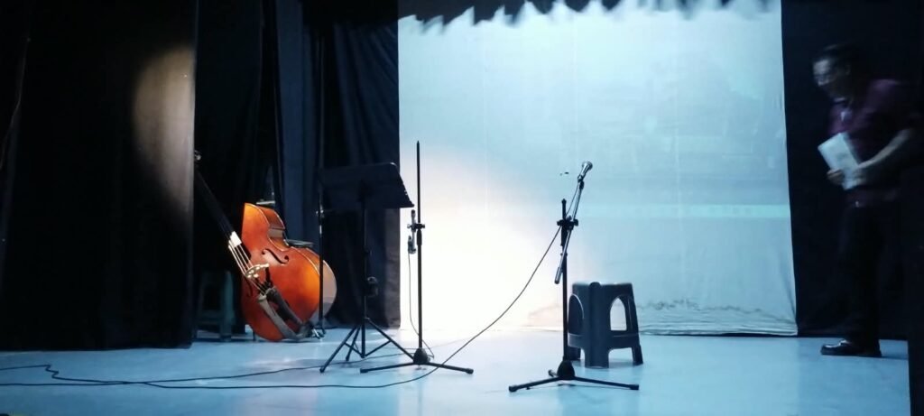 Escenario de la Tardeada Surrealista del Poeta Muerto con contrabajo, micrófonos y atriles en Cuautitlán Izcalli.