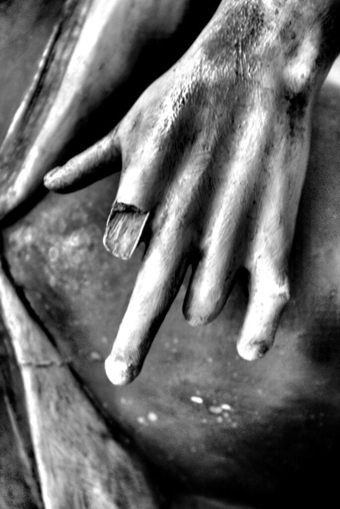 Fotografía en blanco y negro de una mano de apariencia escultórica, desgastada y con un dedo deteriorado, que acompaña el poema Saudade I. (Solo), de Éric Marváz.